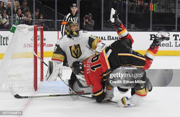 Marc-Andre Fleury of the Vegas Golden Knights looks on as Matthew Tkachuk of the Calgary Flames falls over Deryk Engelland of the Golden Knights in...