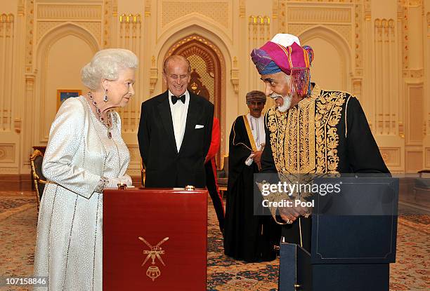 Queen Elizabeth II and Prince Philip, Duke of Edinburgh are presented with a gold musical Faberge style egg by the Sultan of Oman, before a State...