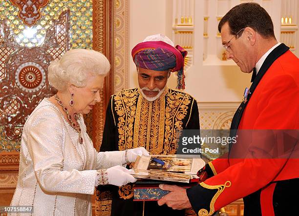 Queen Elizabeth II presents the Sultan of Oman, His Majesty Sultan Qaboos bin Said with two silver ornate framed pictures of herself and the Duke of...