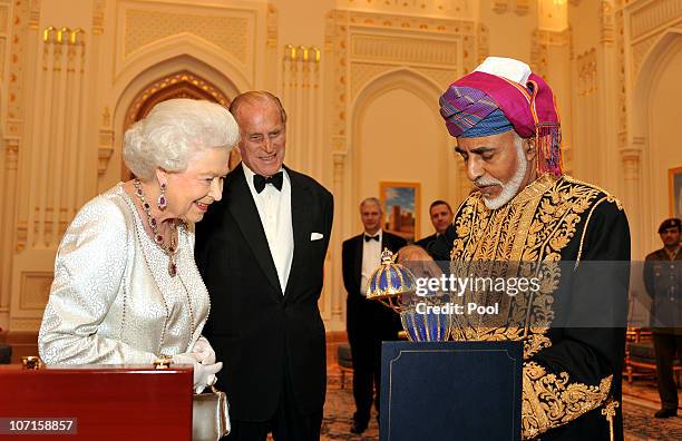 Queen Elizabeth II and Prince Philip, Duke of Edinburgh are presented with a gold musical Faberge style egg by the Sultan of Oman, before a State...