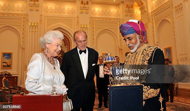 Queen Elizabeth II and Prince Philip, Duke of Edinburgh are presented with a gold musical Faberge style egg by the Sultan of Oman, before a State...
