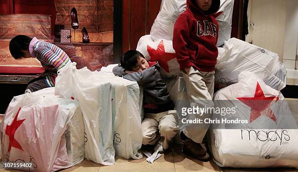 Children wait with shopping bags inside Macy's department store on "Black Friday" shopping day November 26, 2010 in New York City. Christmas shopping...