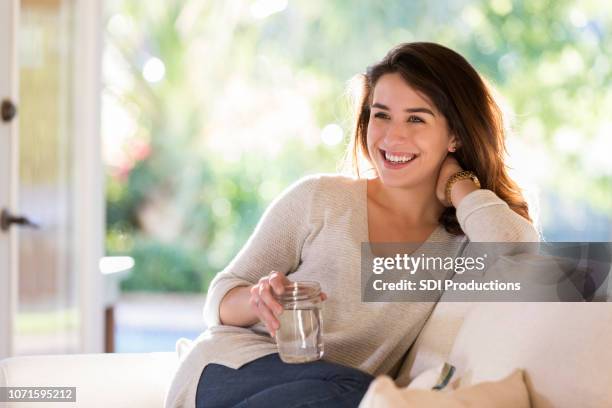 frau tagträumen während sie gemütlich auf dem sofa - water cooler stock-fotos und bilder