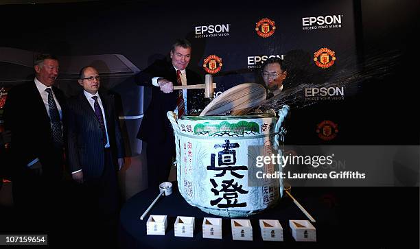 Epson Global President Mr Minoru Usui breaks a sake barrell with Manchester United Chief Executive David Gill watched by Sir Alex Ferguson during a...