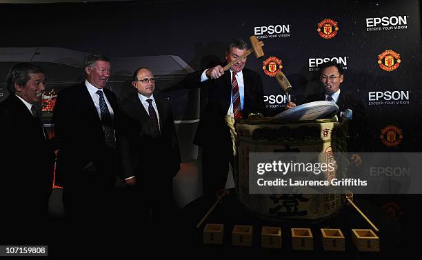 Epson Global President Mr Minoru Usui breaks a sake barrell with Manchester United Chief Executive David Gill watched by Sir Alex Ferguson during a...