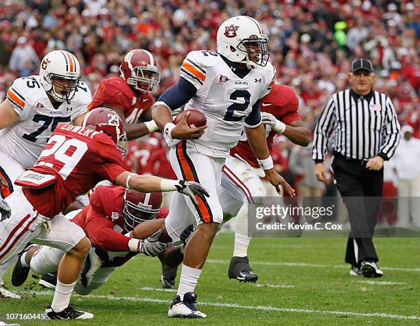 Quarterback Cam Newton of the Auburn Tigers rushes upfield away from Will Lowery and Marcell Dareus of the Alabama Crimson Tide at Bryant-Denny...