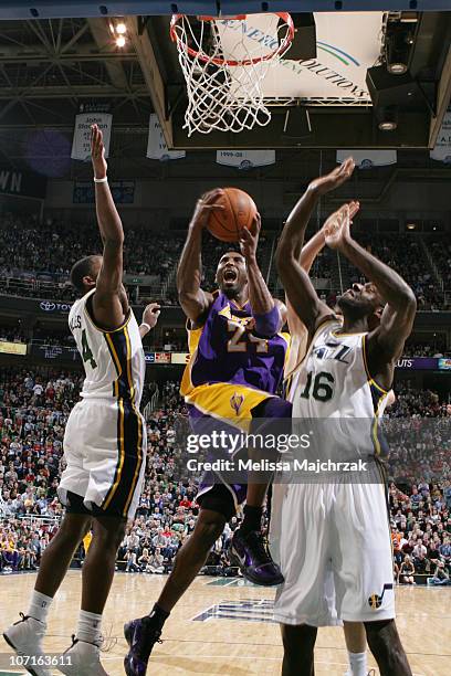 Kobe Bryant of the Los Angeles Lakers lays it up against C.J. Miles and Francisco Elson of the Utah Jazz at EnergySolutions Arena on November 26,...