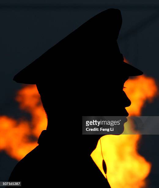 Military officer looks on from his position as the flame burns behind him during the Closing Ceremony at Haixinsha Square on day fifteen of the 16th...