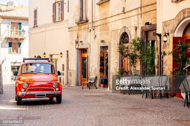 old red small vintage car on the street of italian city on a sunny day - italiano fotografías e imágenes de stock