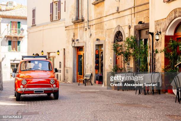 old red small vintage car on the street of italian city on a sunny day - ヨーロッパ　町並み ストックフォトと画像