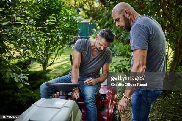 two men with riding mower in garden - examining lawn stock pictures, royalty-free photos & images