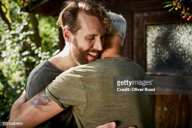 two happy men embracing at garden shed - erwachsene person stock-fotos und bilder