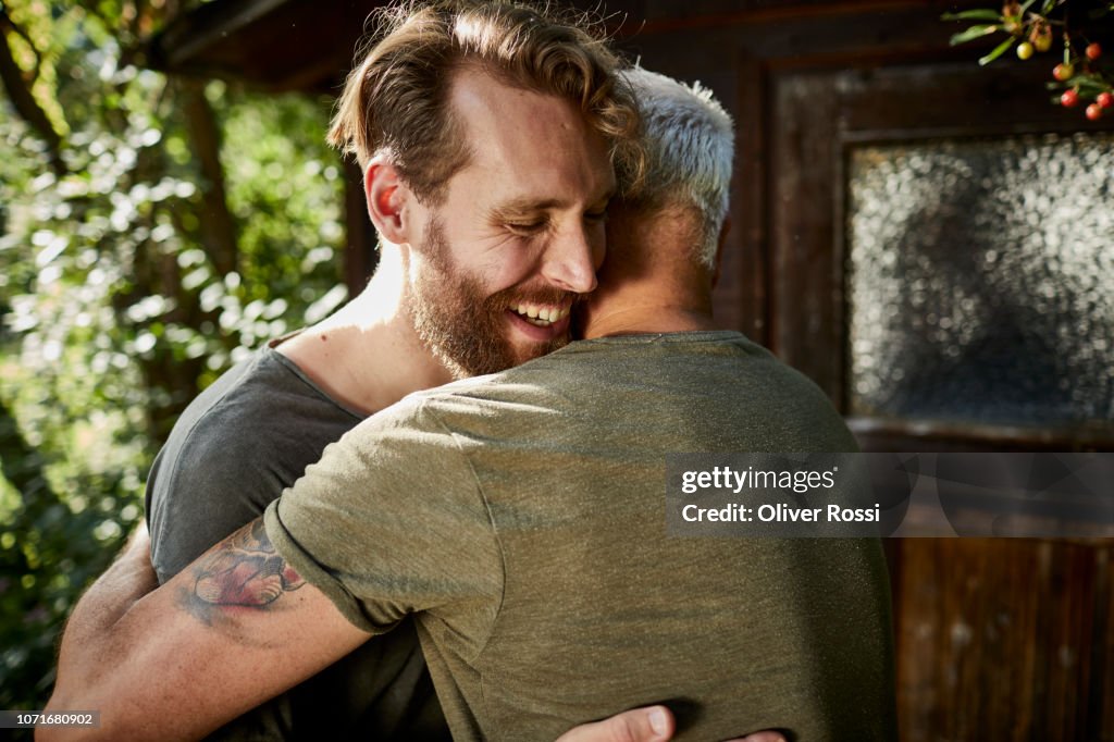 Two happy men embracing at garden shed