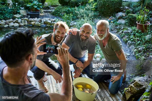happy friends taking a cell phone picture at garden pond - facial hair stock pictures, royalty-free photos & images