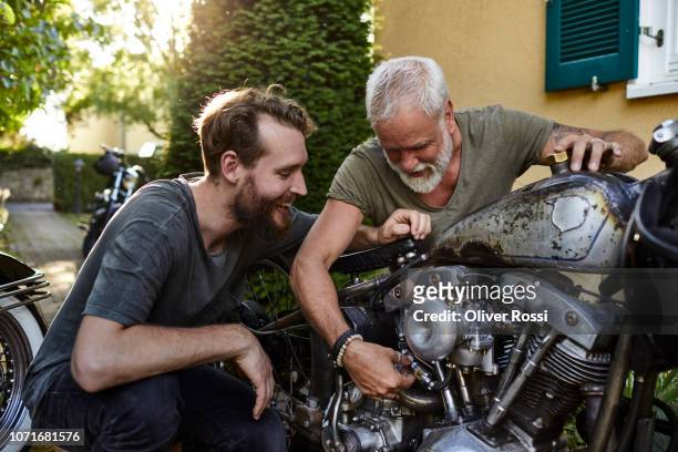 two happy men with motorcycle in garden - freizeit stock-fotos und bilder