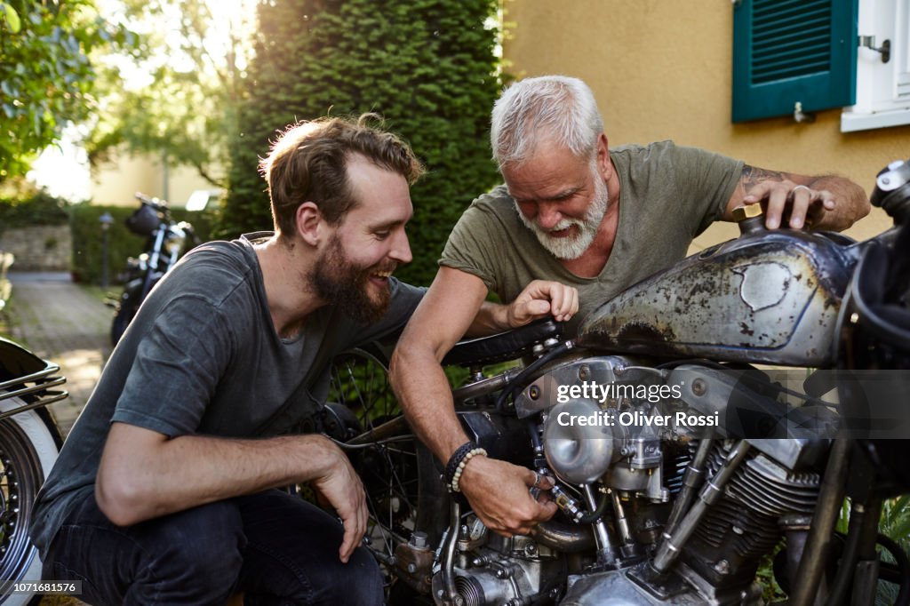 Two happy men with motorcycle in garden