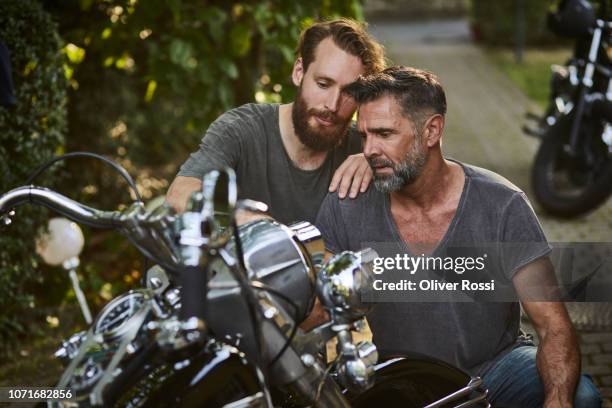 two serious men examining motorcycle in garden - facial hair stock pictures, royalty-free photos & images