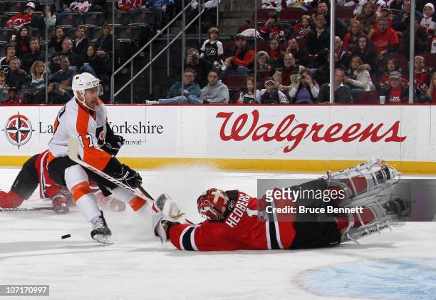 Johan Hedberg of the New Jersey Devils makes a third period save against Jeff Carter of the Philadelphia Flyers at the Prudential Center on November...