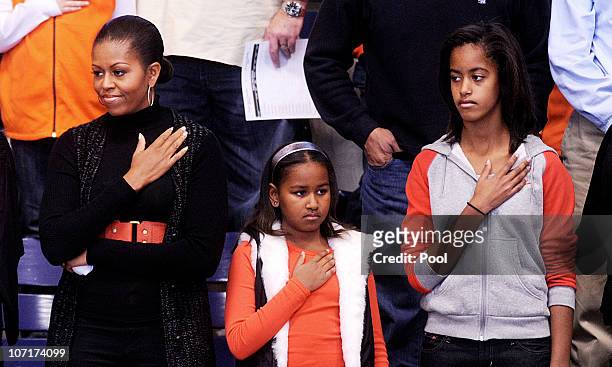 First lady Michelle Obama and daughters Malia and Sasha stand for the National Anthem during a college basketball game at Howard University November...