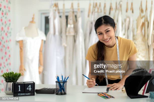 portrait of wedding dress store owner with a diary. asian woman design bridal boutique in shop. - bridal shop stockfoto's en -beelden