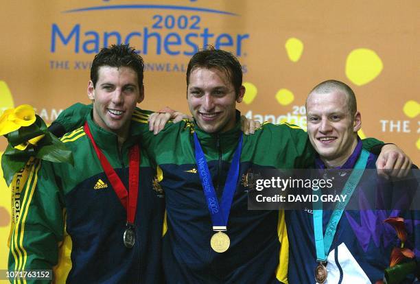 Australia's Ian Thorpe smiles with team mate and silver medalist Grant Hackett as they pose for pictures with Scotland's bronze medalist Graeme Smith...