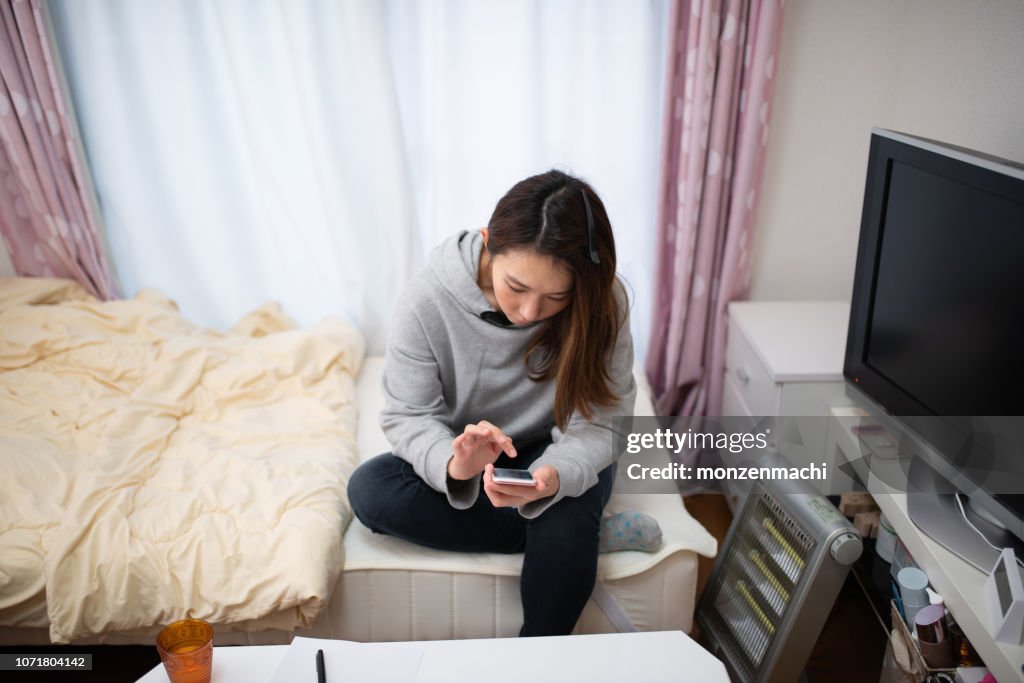 女性家でスマート フォンで電子メールを送信します。