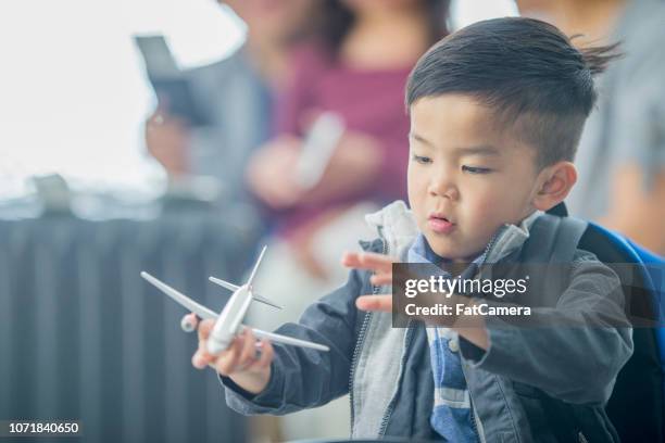 little boy playing with toy airplane at the airport - canadian passport stock pictures, royalty-free photos & images