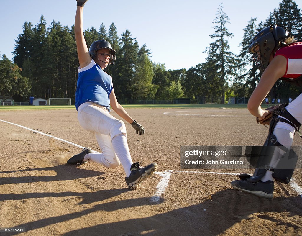 Softball player slides at home plate.