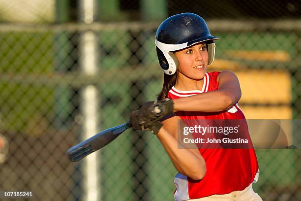 girl softball player swings a bat. - baseball helmet ストックフォトと画像