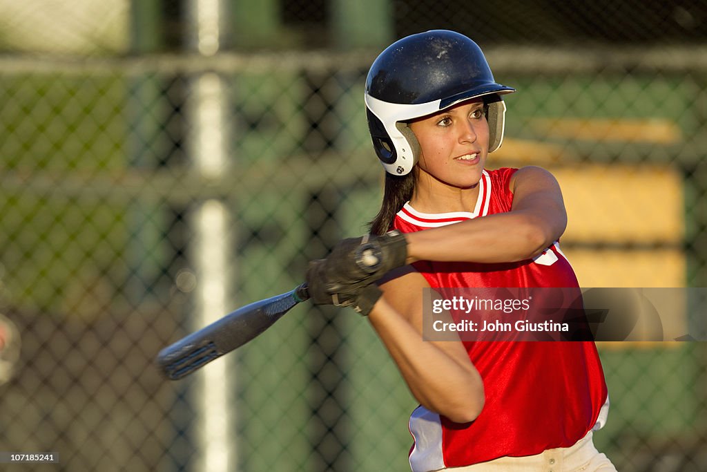 Girl softball player swings a bat.