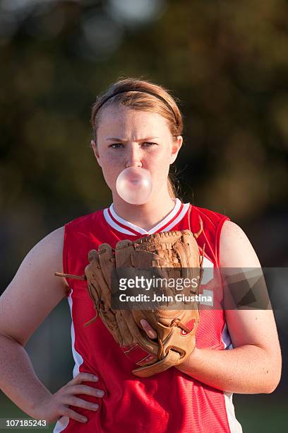 girl softball player blowing a bubble. - girls softball stock pictures, royalty-free photos & images