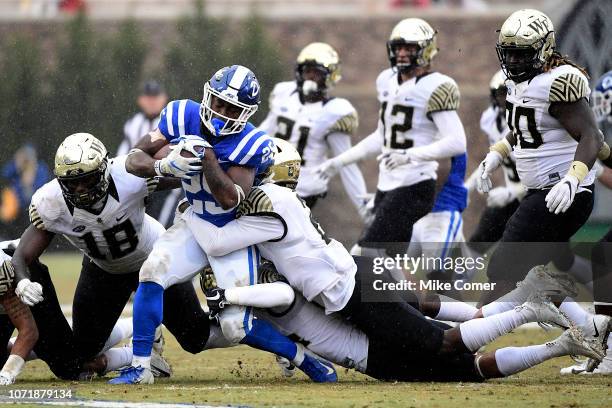 Defensive back Cameron Glenn of the Wake Forest Demon Deacons leads a tackle of running back Deon Jackson of the Duke Blue Devils during their...