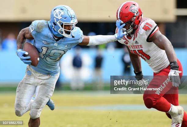 Dazz Newsome of the North Carolina Tar Heels stiff-arms Isaiah Moore of the North Carolina State Wolfpack during the second half of their game at...