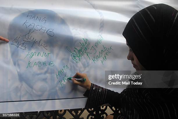 Muslim lady signing on the board demanding to hang on 26/11 terrorist Ajmal Kasab at a memorial outside the Taj Mahal Palace hotel on the second...