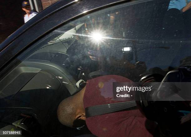 Man bends over to avoid the media on November 29, 2010 as he is driven into the Wynberg Magistrate's Court by members of the South African Police...