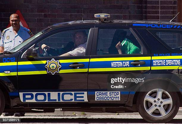 Man hides in a green jacket to avoid the media on November 29, 2010 as he is driven into the Wynberg Magistrate's Court by members of the South...