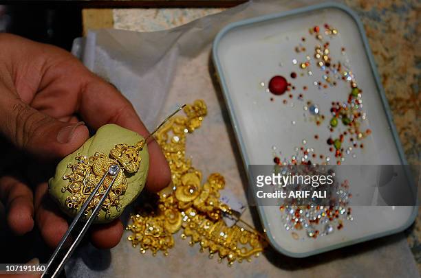 Pakistani jeweller prepares a necklace at his gold workshop in Lahore on November 11, 2010. Gold has surged to fresh pinnacles this week, boosted by...