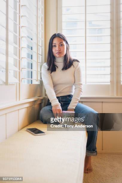 young woman inside home wearing sweater drinking from a mug - hot vietnamese women stock pictures, royalty-free photos & images