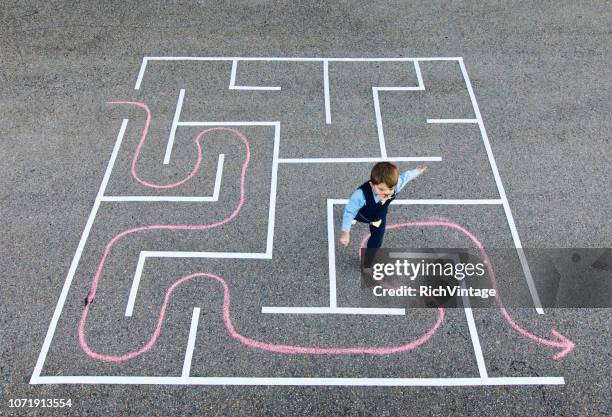 jonge jongen zakenman uitgevoerd in de doolhof - wrong way stockfoto's en -beelden