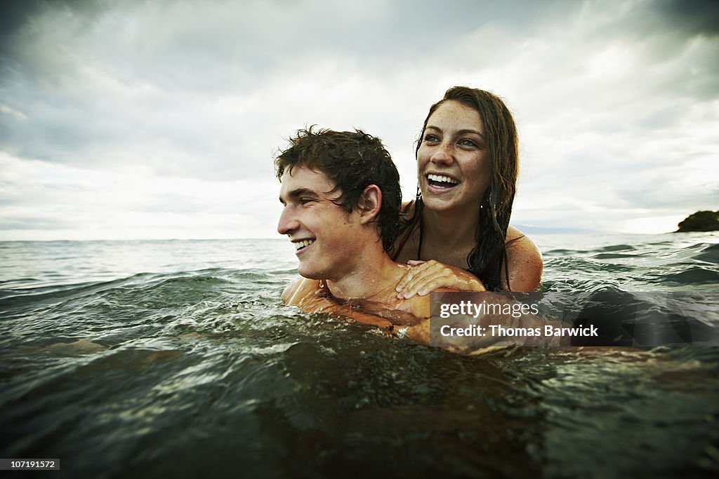 Teenage couple embracing and laughing in ocean