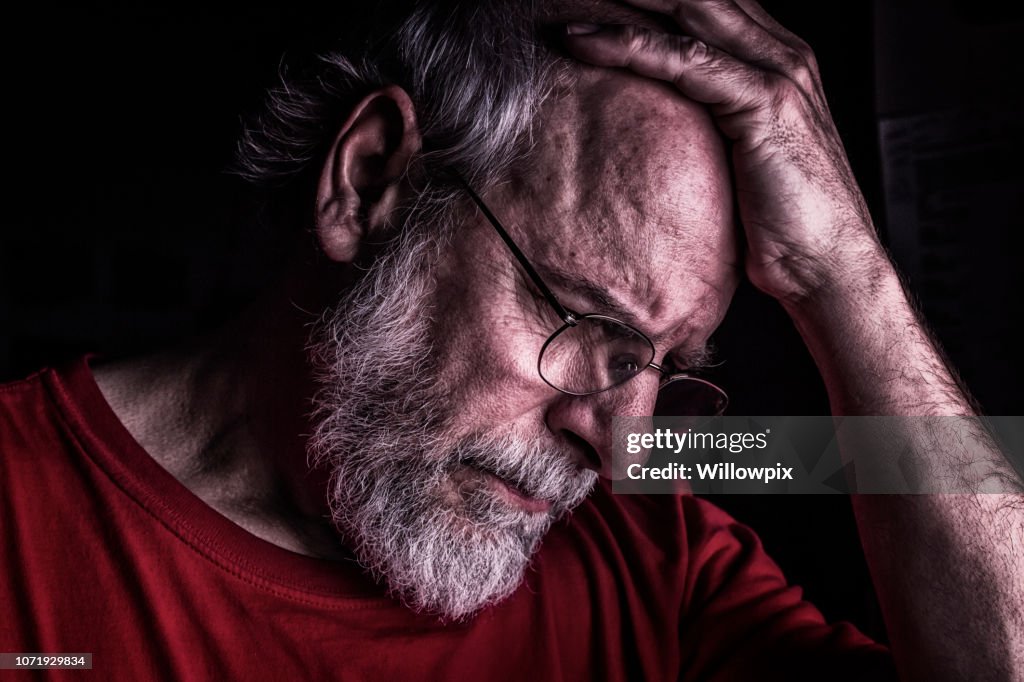 Hombre adulto Senior angustiada sosteniendo la cabeza