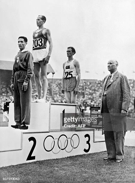 Gold winner of the Olympics 10000 meters Czech Emil Zatopek , Second French Alain Mimoun and third Swedish Bertil Albertsson pose on the podium...