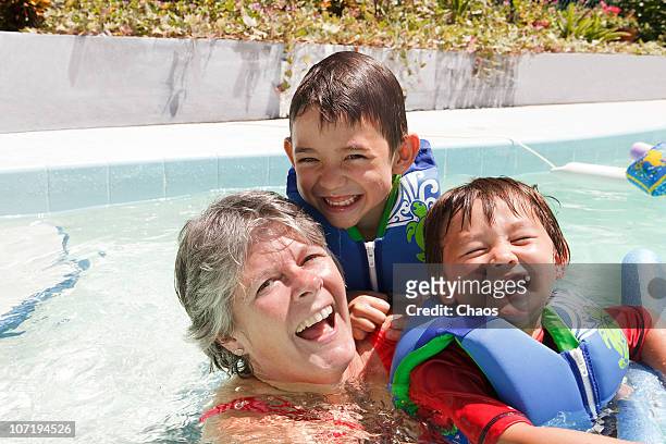 grandmother and grandsons in a pool - swim safety stock-fotos und bilder