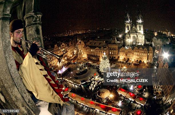Traditional dressed man plays trumpet on November 29, 2010 from the Old Town tower of Prague, above the traditional Christmas market set in front of...