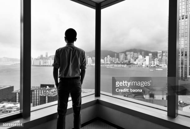 businessman looking at city through office window - black and white office stock pictures, royalty-free photos & images