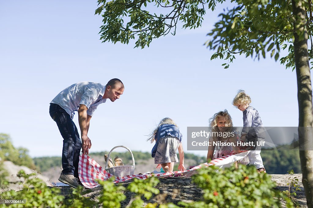 Family laying down blanket for picnic