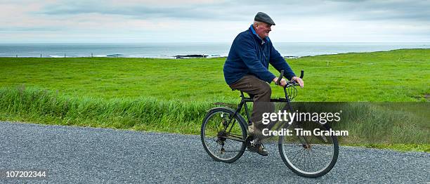 Local Irish man cycling traditional bicycle along country lane in County Clare, Ireland