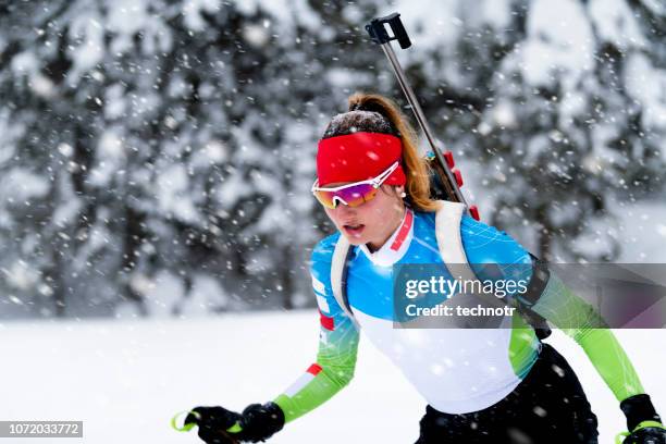 front view of female biathlon competitor practicing cross-country skiing in snowstorm - biathlon ski stock pictures, royalty-free photos & images