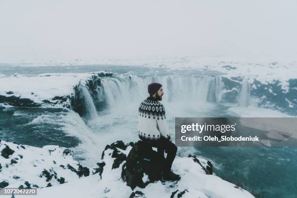 homme regardant une vue panoramique de la chute d’eau en hiver - parc national de skaftafell photos et images de collection
