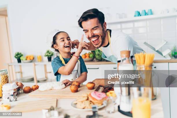 father and daughter getting messy on the kitchen - two cupcakes stock pictures, royalty-free photos & images